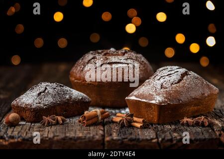 Drei Weihnachtsbrot, Stollen, auf einem Holztisch mit Struktur, vor dem Hintergrund von verschwommenen Lichtern in Bokeh. Zu Weihnachten. Stockfoto