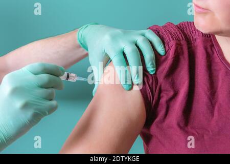 Die Krankenschwester hält die Spritze und verabreicht die Injektion an die Patientin. Frau, die im Impfzentrum impft. Impfung in der Schulter. Sicherheit vor Coronavirus Stockfoto