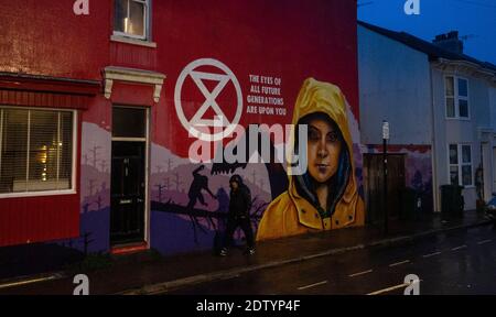 Brighton UK 22. Dezember 2020 - EIN Mann geht an einem Wandgemälde vorbei, das Greta Thunberg und das Aussterben zeigt.Rebellion Klimaproteste in Brighton als schwere Regenschauer über den Südosten an diesem Abend ziehen : Credit Simon Dack / Alamy Live News Stockfoto