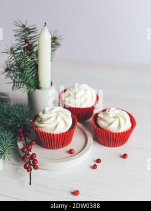 Leckere Cupcakes mit Fichtenzweigen und roten Beeren auf weißem Hintergrund dekoriert. Süßigkeiten für die Feier Weihnachten. Urlaub umweltfreundliche concep Stockfoto