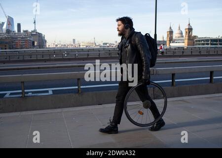 Ein Mann geht mit einem Fahrrad über die London Bridge Stockfoto