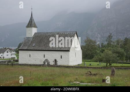 Eidfjord alte Kirche, eine historische weiße christliche Kirche, erbaut im 14. Jahrhundert, an einem schönen sonnigen Tag, in einer bergigen Landschaft in Norwegen Stockfoto