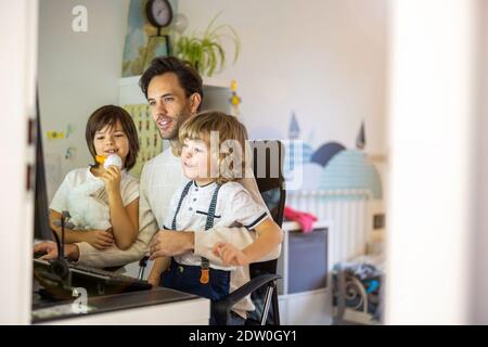 Vater versucht, von zu Hause aus mit seinen Kindern zu arbeiten Stockfoto