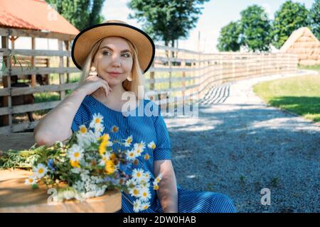 Cottagecore, Landästhetik, Landwirtschaft, Farmcore, Countrycore, langsames Leben. Junges Mädchen in Bauernkleid und mit Blumen genießen die Natur auf Stockfoto