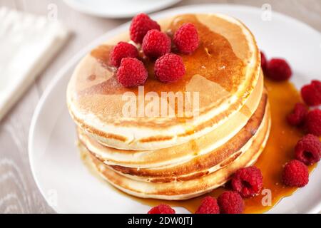 Pfannkuchen mit Beeren und Ahornsirup auf einem Teller. Stockfoto