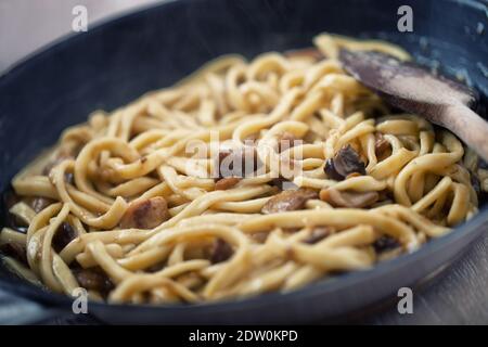 Kochen Sie frische Tagliatelle mit Pilzen in einer Pfanne. Stockfoto