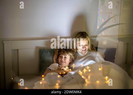 Mutter und Sohn nutzen digitales Tablet zusammen in der Nacht Bett Stockfoto