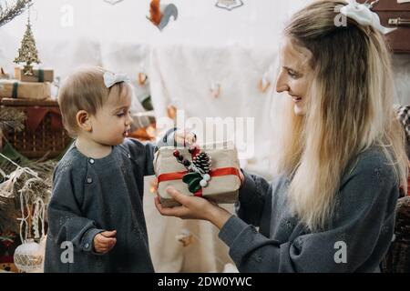 Boxtag, Sankt Nikolaus Tag. Baby Mädchen und Mama ausgepackte Boxen mit Geschenken in Weihnachtsbaum Dekorationen zu Hause. Frohe Weihnachten und ein glückliches Neues Stockfoto