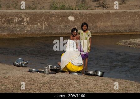 Sasan, Gir Sanctuary, Gujarat, Indien-2. Februar 2010: Indische Familie waschen die Kochutensilien im Hiran Fluss. Stockfoto