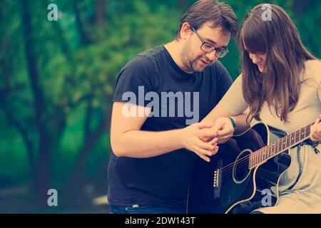 Bruder lehrt Schwester Gitarre in der Natur zu spielen Stockfoto