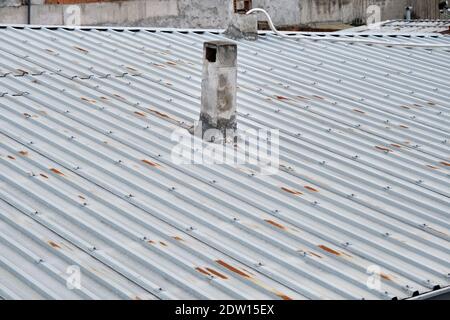 Dach des Hauses aus Metallpaneelen. Korrosion besteht auf Dach und alten Stil Schornstein Stapel bei bewölktem Wetter. Stockfoto
