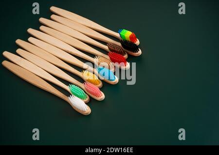 Ein Set umweltfreundlicher antibakterieller Zahnbürsten aus Bambusholz auf dunkelgrünem Hintergrund. Umwelttrends. Stockfoto