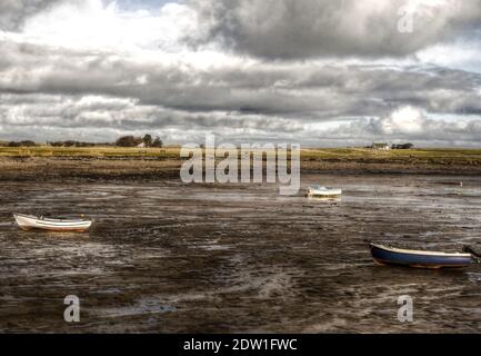 Boote liegen bei Ebbe auf dem Schlamm im Hafen von Lindisfarne im Norden von Northumberland in England. Stockfoto