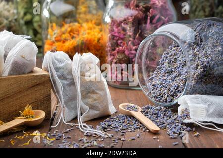 Filter Teebeutel mit Heilkräutern gefüllt. Glas mit trockenen Lavendelblüten für die Herstellung von Kräutertee, Gläser mit verschiedenen gesunden Kräutern auf dem Hintergrund. Alt Stockfoto