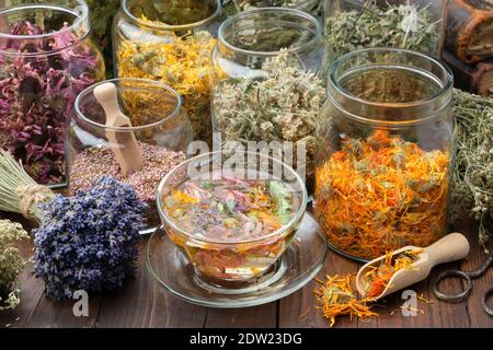 Tasse gesunden Ringelblume Tee, Gläser von trockenen Heilkräutern - Heidekraut, Ringelblume, Konelblüten, melisse, Lindenbaumblumen, Bund von trockenen Lavendel auf wo Stockfoto