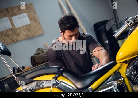 Ein starker Biker repariert sein Motorrad in der Garage. Der Innenraum der Werkstatt Stockfoto