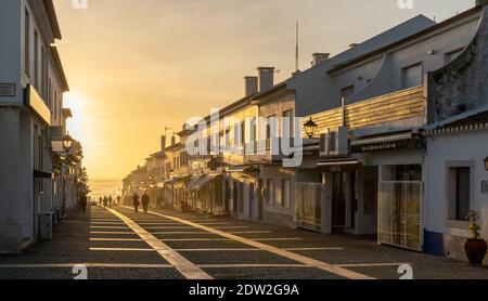 Porto Covo, Portugal - 20. Dezember 2020: Menschen genießen einen Abendspaziergang auf der Rua Vasco da Gama in Porto Covo im goldenen Abendlicht Stockfoto