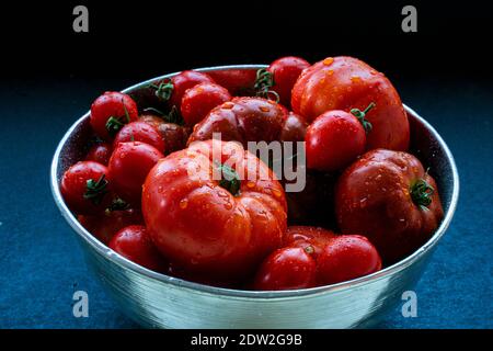 Verschiedene Arten von frischen Tomaten in Kupferschüssel. Stockfoto