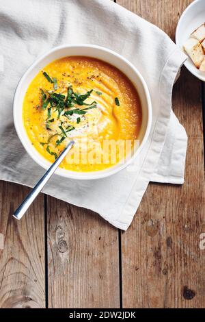 Kürbiscremesuppe mit Kräutern auf rustikalem Holzhintergrund. Stockfoto