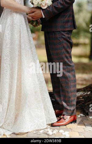 Gesichtsloser Bräutigam und Braut stehen einander gegenüber und halten sich gegenseitig die Hände. Glückliches Jungvermählte bei der Hochzeitszeremonie Stockfoto