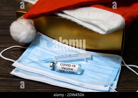 Weihnachtsfeier während COVID-19 Coronavirus Pandemie. Medizinische Maske, Geschenk-und Impfstoffflasche für Weihnachten Urlaub. Konzept der Wintersaison, Gesundheit, Stockfoto