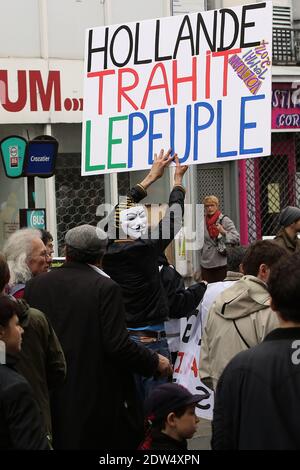 Ein Mann, der eine Guy Fawkes Maske trägt, hält ein Plakat mit der Aufschrift "Holland verrät das Volk" während einer Kundgebung am 1. Mai 2014 in Paris, Frankreich. Foto von Stephane Lemouton/ABACAPRESS.COM Stockfoto