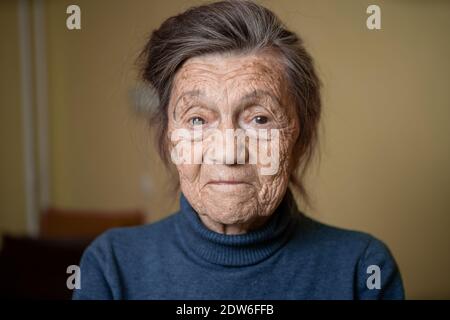 Ältere niedliche Frau von neunzig Jahre alt Kaukasisch mit grauen Haaren und faltigen Gesicht sieht in der Kamera, nette Art Look und lächelt.Reife Großmutter im Ruhestand Stockfoto