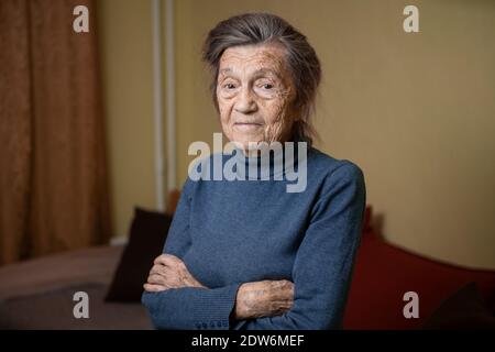 Ältere niedliche Frau von neunzig Jahre alt Kaukasisch mit grauen Haaren und faltigen Gesicht sieht in der Kamera, nette Art Look und lächelt.Reife Großmutter im Ruhestand Stockfoto