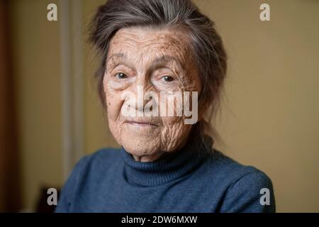 Ältere niedliche Frau von neunzig Jahre alt Kaukasisch mit grauen Haaren und faltigen Gesicht sieht in der Kamera, nette Art Look und lächelt.Reife Großmutter im Ruhestand Stockfoto