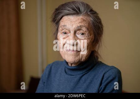 Ältere niedliche Frau von neunzig Jahre alt Kaukasisch mit grauen Haaren und faltigen Gesicht sieht in der Kamera, nette Art Look und lächelt.Reife Großmutter im Ruhestand Stockfoto