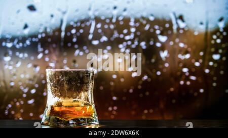 Ein Glas Whiskey, Brandy auf der Theke, ein alkoholisches Getränk in einem Glas Whiskey.vor dem Hintergrund von Regentropfen. Stockfoto