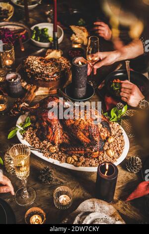 Freunde feiern über festlichen Tisch mit ganzen gerösteten Truthahn mit Reis und Kastanien, Schokolade gebündelt Kuchen und Kerzen, Backstein Wand Hintergrund. Chr Stockfoto