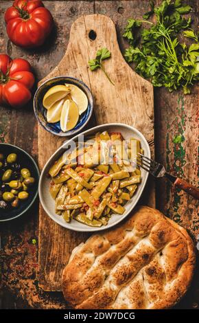 Vorspeise mit Tomate, Olivenöl und Fladenbrot auf dem rustikalen Holztisch, Blick von oben. Türkisch Stockfoto