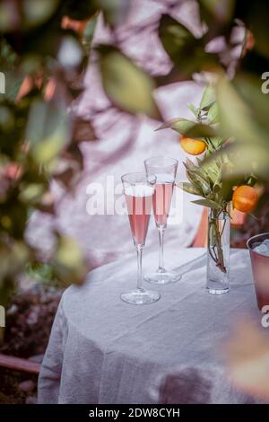 Tisch im Garten neben dem Orangenbaum mit zwei Gläsern Sekt. Stockfoto