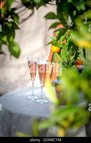 Tisch im Garten neben dem Orangenbaum mit zwei Gläsern Sekt. Stockfoto