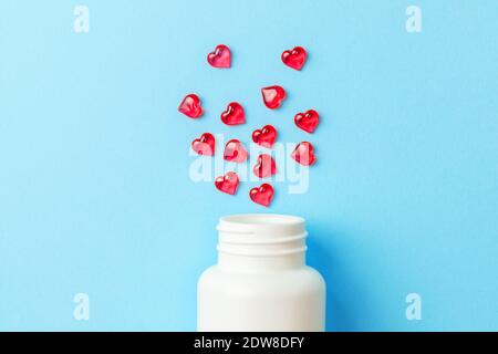 Pillen der Liebe. Rote Pillen in Herzform mit Flasche auf blauem Hintergrund. Stockfoto