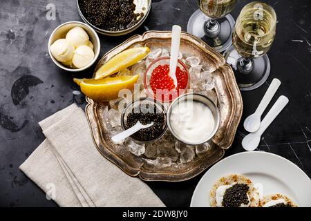 Rot und Schwarz Caviar, Mini Pancakes und Sour Cream Holiday Party Vorspeise auf dunklem Marmor Hintergrund Stockfoto
