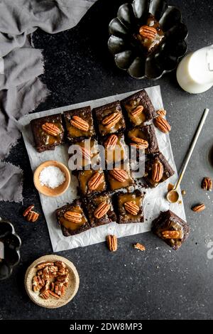 Turtle Brownies mit gesalzenem Karamell und Pecan Topping in einem Flachlay. Stockfoto