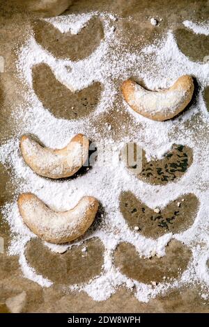 Hausgemachte traditionelle Weihnachten Mürbeteig Cookies Vanille Crescents mit Puderzucker auf Backpapier. Draufsicht Stockfoto