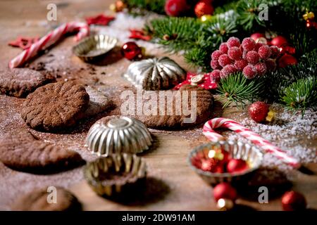 Hausgemachte traditionelle Weihnachten Mürbeteig Cookies Schokolade Crescents mit Kakao Puderzucker in Keramik-Platte mit Cookie-Formen, Tanne, rote Weihnachten st Stockfoto