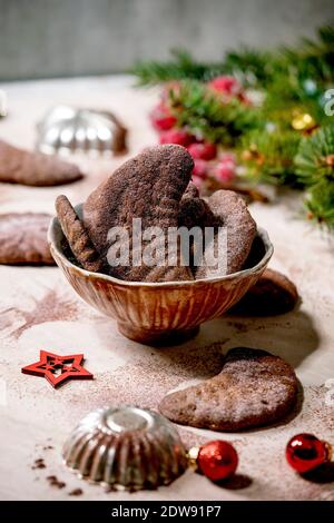 Hausgemachte traditionelle Weihnachten Mürbeteig Cookies Schokolade Crescents mit Kakao Puderzucker in Keramik-Platte mit Cookie-Formen, Tanne, rote Weihnachten st Stockfoto