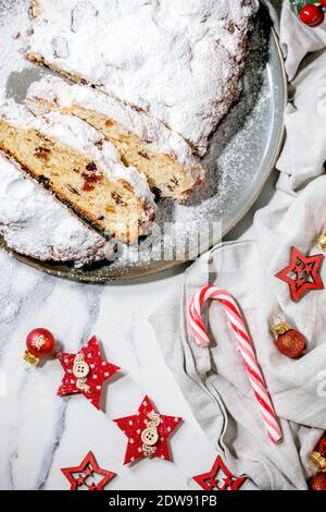 Traditionelles hausgemachtes deutsches Weihnachtsgebäck Stollenkuchen Brot auf Teller mit Weihnachtsdekorationen und Tannenzweigen auf weißem Marmorboden. Fla Stockfoto