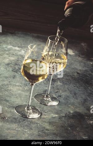 Weißer Wein in die Gläser auf dem Stein gießen Stockfoto