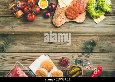 Hausgemachte Hamburger. Rohes Rindfleisch Frikadellen, Sesam Brötchen mit anderen Zutaten für die Hamburger auf Holz- Hintergrund Stockfoto