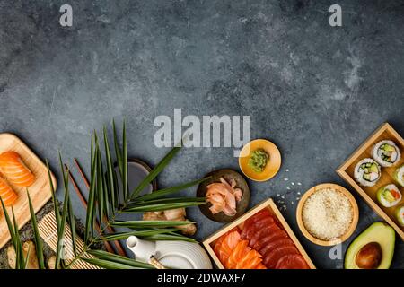 Ein Schuss Zutaten für Sushi und zubereitete Maki und Nigiri auf dunkelblauem Hintergrund. Roher Lachs und Thunfisch Pieses, Reis, Avocado, eingelegter Ingwer Stockfoto