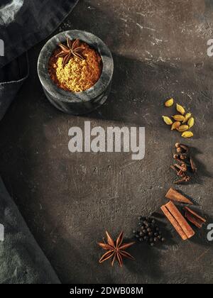 Indische oder pakistanische Masala Pulver und Gewürze auf schwarzem Hintergrund. Kleine schwarze Marmorschale mit trockenem Curry Garam Masala Mix Gewürzmischung, Zimtstangen Stockfoto
