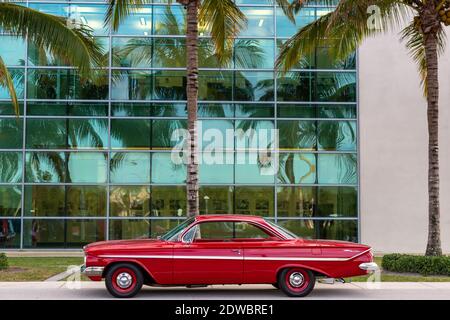 Ein rotes Chevrolet Bel Air 'Bubble Top' Coupé aus dem Jahr 1961 sitzt mit Palmen vor dem Elliott Museum auf der Hutchinson Island in Stuart, Florida, USA. Stockfoto