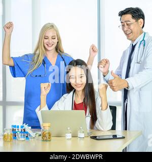 Gruppe von Ärzten tragen formelle weiße Mantel und blauen Peelings Anzug, Daumen hoch für den Erfolg im Krankenhaus. Fachkräfte im Gesundheitswesen. Stockfoto