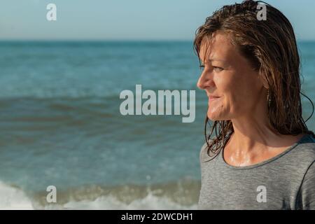 Portrait der Frau im Profil Blick auf das Meer und lächelnd, Meeresbett Stockfoto