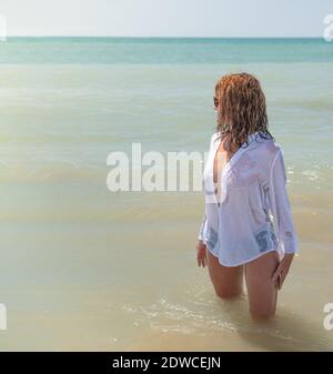 Frau am Strand überrascht von einer Welle, spritzte. Auf ihrem Rücken, Konzept Urlaub Stockfoto